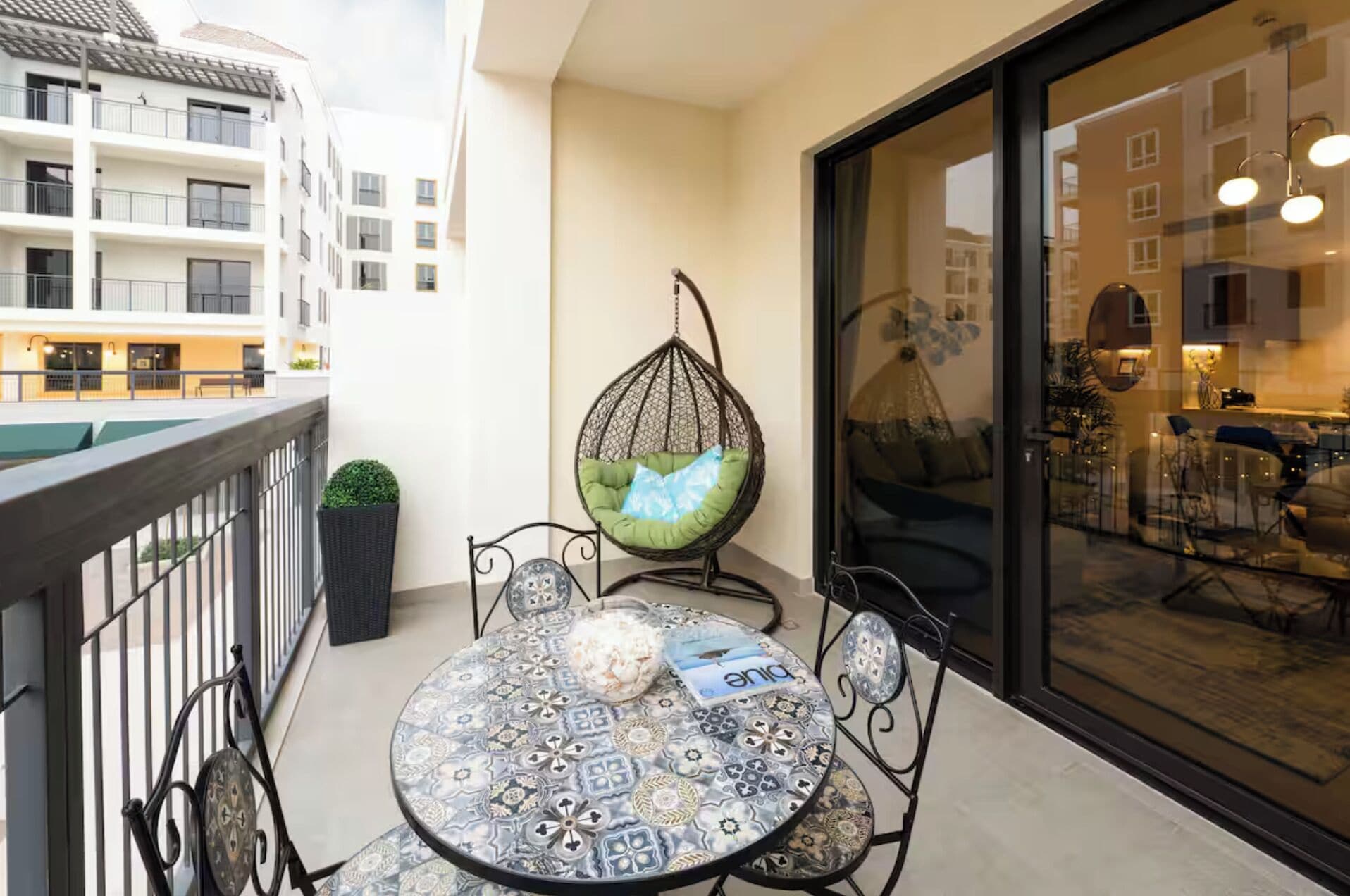 Ein Balkon mit rundem Tisch, Stühlen, einer Hängematte und einem Blumentopf.