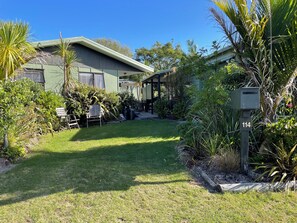Ein Wohnhaus mit überdachter Terrasse, Rasenfläche und Briefkasten mit der Nummer 114.