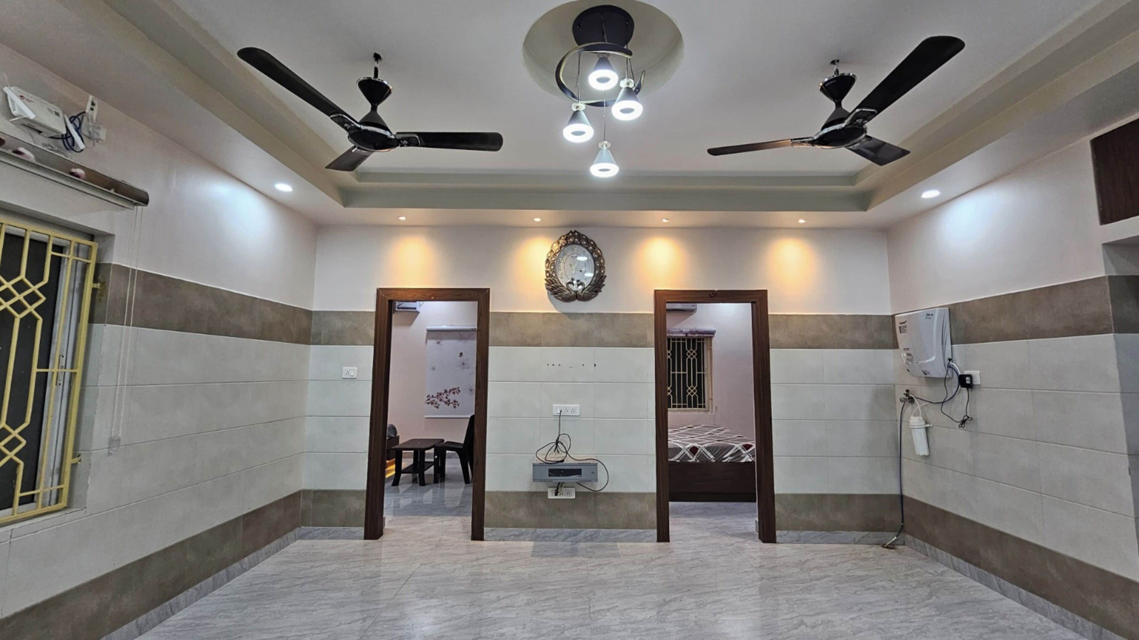 A hotel lobby with a marble floor, ceiling fans, a clock, and a water dispenser.