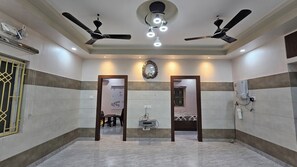 A hotel lobby with a marble floor, ceiling fans, a clock, and a water dispenser. - Kothari Guest House (Puri)