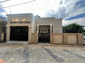 Un edificio con un letrero que dice 'Kothari Guest House' y una entrada protegida por una reja.