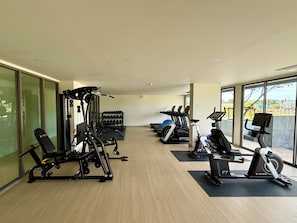 Ein Fitnessstudio mit Laufbändern, Gewichten und einer Bank.