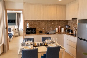 Una habitación de hotel compacta con kitchenette, comedor y cama.