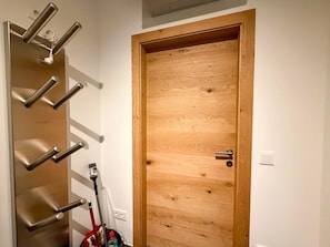 Une porte en bois, dotée d’une poignée en métal et d’un porte-manteau fixé au mur, à sa gauche.