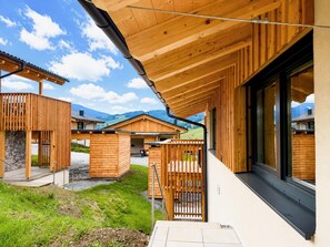 A modern wooden building with a covered outdoor area and a view of the surrounding landscape. - Nice ski-in-ski-out lodge with sauna and balcony (Sankt Lambrecht)