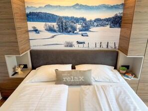 A hotel room with a bed, a pillow with 'time to relax' text, a remote control, a book, and a wall-mounted painting of a snowy landscape. - Nice ski-in-ski-out lodge with sauna and balcony (Sankt Lambrecht)