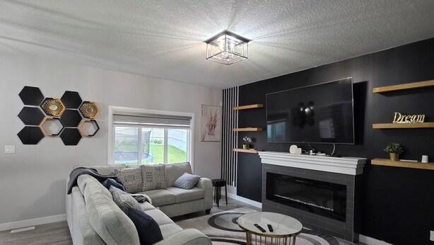A modern living room with a sofa, a coffee table, and a fireplace. - Treasure Villa: Prestigious Lodge | King Bed | AC (Edmonton)