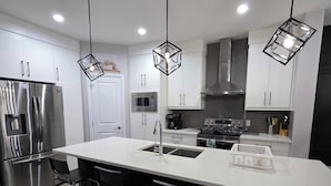 A modern kitchen with a central island, stainless steel appliances, and pendant lighting. - Treasure Villa: Prestigious Lodge | King Bed | AC (Edmonton)