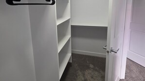 A walk-in closet with open shelving and a hanging rod. - Treasure Villa: Prestigious Lodge | King Bed | AC (Edmonton)