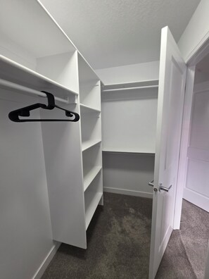 Ein begehbarer Kleiderschrank mit offenen Regalen und einer Kleiderstange.