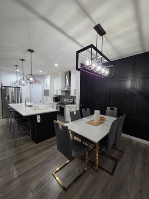 A modern kitchen with a central island, stainless steel appliances, and pendant lighting. - Treasure Villa: Prestigious Lodge | King Bed | AC (Edmonton)