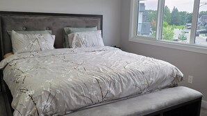 A bedroom with a bed, a bench, a window, and a view of the outside. - Treasure Villa: Prestigious Lodge | King Bed | AC (Edmonton)