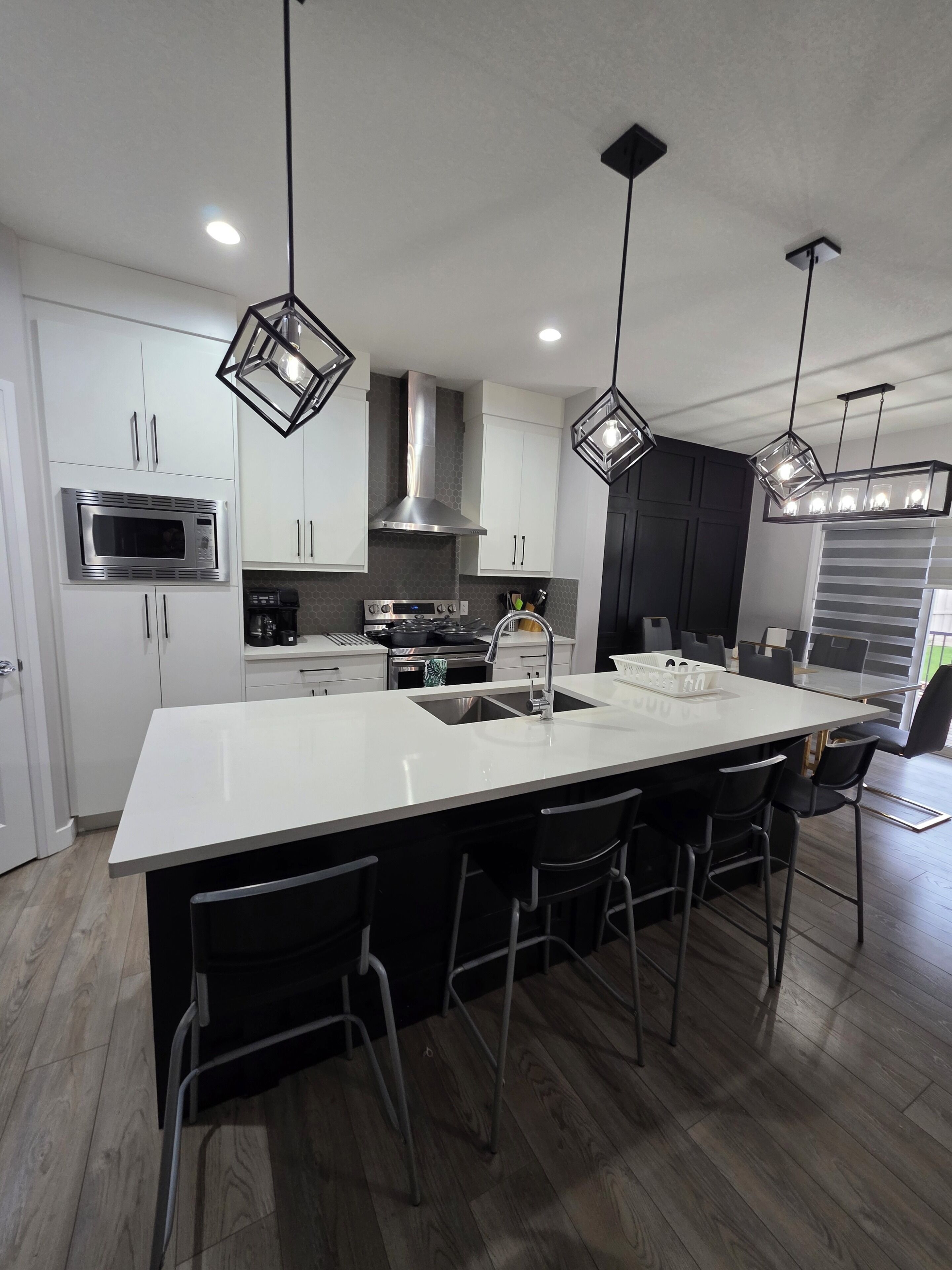 A modern kitchen with a central island, stainless steel appliances, and pendant lighting.