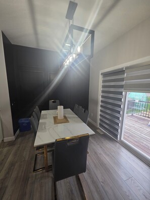 A modern dining area with a marble table, black chairs, and a ceiling light fixture. - Treasure Villa: Prestigious Lodge | King Bed | AC (Edmonton)