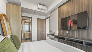 Ein modernes Schlafzimmer mit einem großen Bett, einem an der Wand montierten Fernseher und einem Holzschrank.