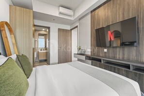 Ein modernes Schlafzimmer mit einem großen Bett, einem an der Wand montierten Fernseher und einem Holzschrank.