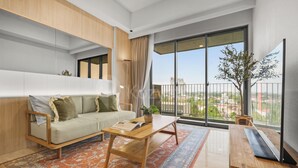 Ein modernes Wohnzimmer mit einer Couch, einem Couchtisch und einem großen Fenster mit Blick auf die Stadt.
