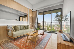 Ein modernes Wohnzimmer mit einer Couch, einem Couchtisch und einem großen Fenster mit Blick auf die Stadt.