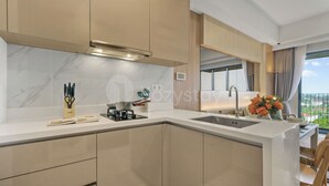 Eine moderne Küche mit Marmor-Spritzschutz, einem eingebauten Herd und einer großen Kochinsel mit Spüle.