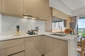 Eine moderne Küche mit Marmor-Spritzschutz, einem eingebauten Herd und einer großen Kochinsel mit Spüle.