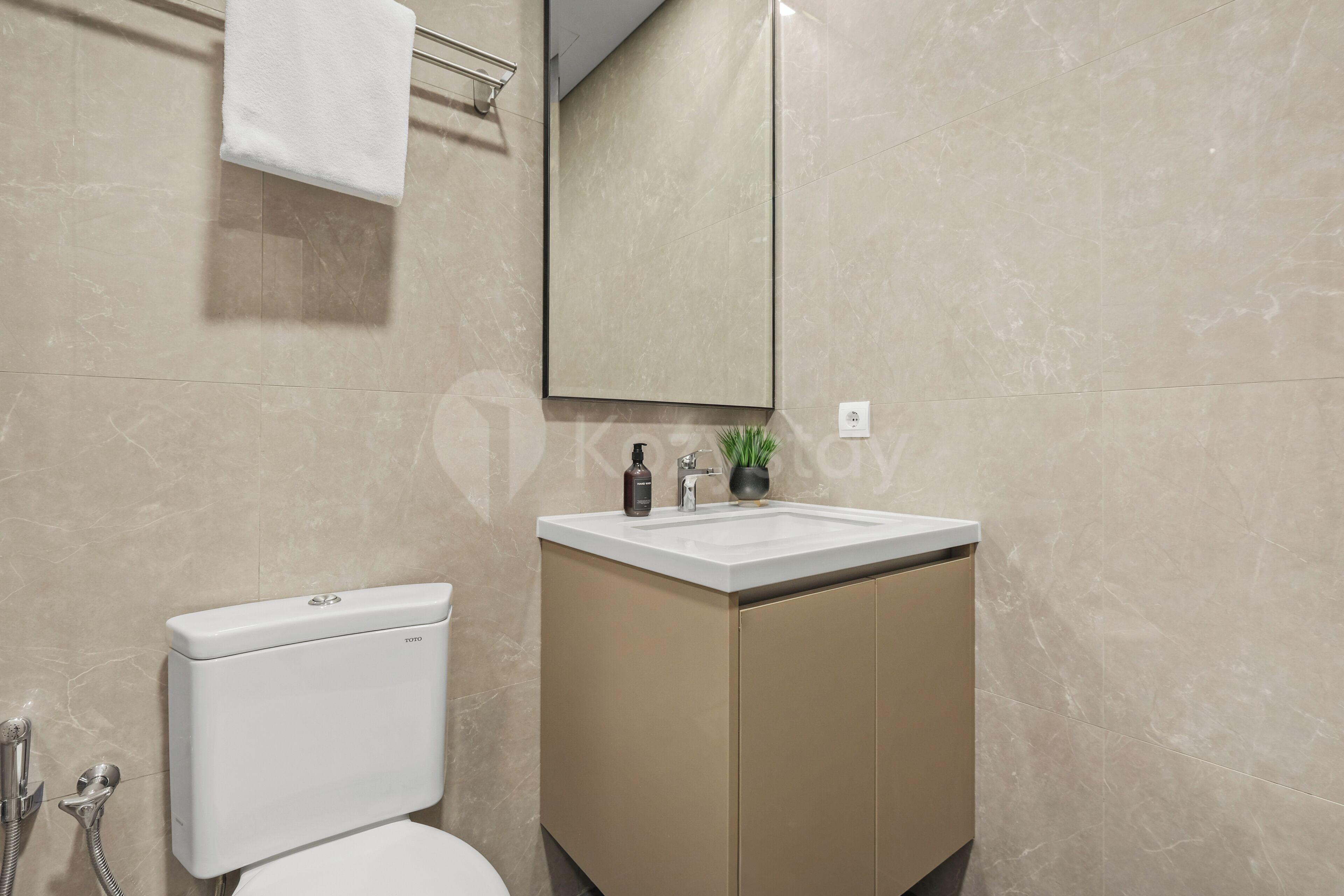 A bathroom with a toilet, a sink, a mirror, and a towel rack.