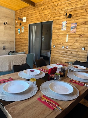 A dining area with wooden walls, a table set for four with plates, glasses, and cutlery.