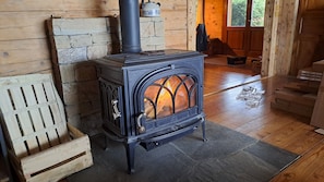 A wood-burning stove with a glass door, a wooden bench, and a rustic interior. - L'Alpage 1884, in the heart of the Grand Bornand ski area (Le Grand-Bornand)