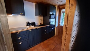A kitchen with dark cabinets, a countertop, a coffee maker, and a sink. - L'Alpage 1884, in the heart of the Grand Bornand ski area (Le Grand-Bornand)