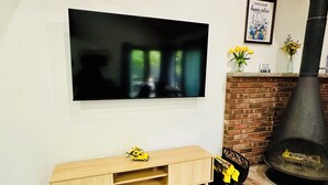 A modern living room with a flat-screen TV mounted on the wall, a wooden TV stand with a toy car, a brick fireplace, and a framed quote on the wall. - Mountainside Townhome close to Waterparks, ski slopes and hiking trails. (Tannersville)
