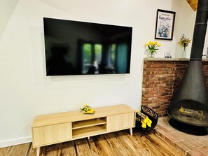 Ein modernes Wohnzimmer mit Fernseher an der Wand, einem Holz-TV-Möbel mit einem Spielzeugauto, einem Kamin aus Ziegelsteinen und einem gerahmten Zitat an der Wand.