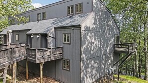 A modern two-story building with a flat roof, multiple windows, and a wooden deck. - Mountainside Townhome close to Waterparks, ski slopes and hiking trails. (Tannersville)
