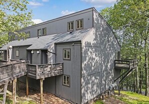 Ein modernes, zweistöckiges Gebäude mit flachem Dach, zahlreichen Fenstern und einer Holzterrasse.