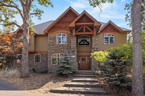 A two-story house with a stone facade, a wooden front porch, and a gabled roof. - Buffalo Teal Lodge|Hot Tub|Resort Amenities (Klamath Falls)