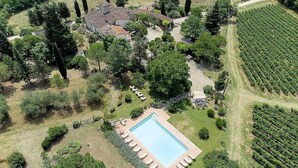 Vista aérea de una propiedad con piscina, rodeada por un patio, un viñedo y un grupo de edificios.