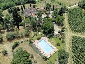An aerial view of a property with a swimming pool surrounded by a patio, a vineyard, and a cluster of buildings. - Casa Camomilla C: A characteristic and welcoming two-story independent house surrounded by meadows and by green hills, with Free WI-FI. (Pontassieve)