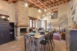 A rustic kitchen with a stone fireplace, wooden beams, and a dining table set for four. - Casa Camomilla C: A characteristic and welcoming two-story independent house surrounded by meadows and by green hills, with Free WI-FI. (Pontassieve)