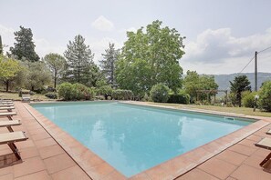 A rectangular swimming pool with a tiled edge, surrounded by lounge chairs and greenery. - Casa Camomilla C: A characteristic and welcoming two-story independent house surrounded by meadows and by green hills, with Free WI-FI. (Pontassieve)