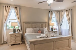 Un dormitorio con cama, mesitas de noche, lámparas y cortinas.