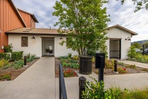 A two-story building with a covered patio area, a small garden with various plants, and a pathway leading to the entrance. - @marbella Lane -amazing 5br Home In Rancho Mission (San Juan Capistrano)