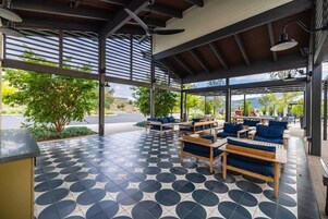 Un espacio al aire libre con mobiliario de madera, piso estampado y vistas del paisaje circundante.