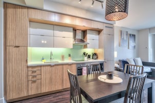 Una cocina moderna con armarios de madera, una isla central y un comedor con sillas.