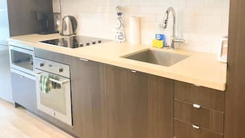 A modern kitchen with a built-in oven, a stovetop, a sink, and wooden cabinets.