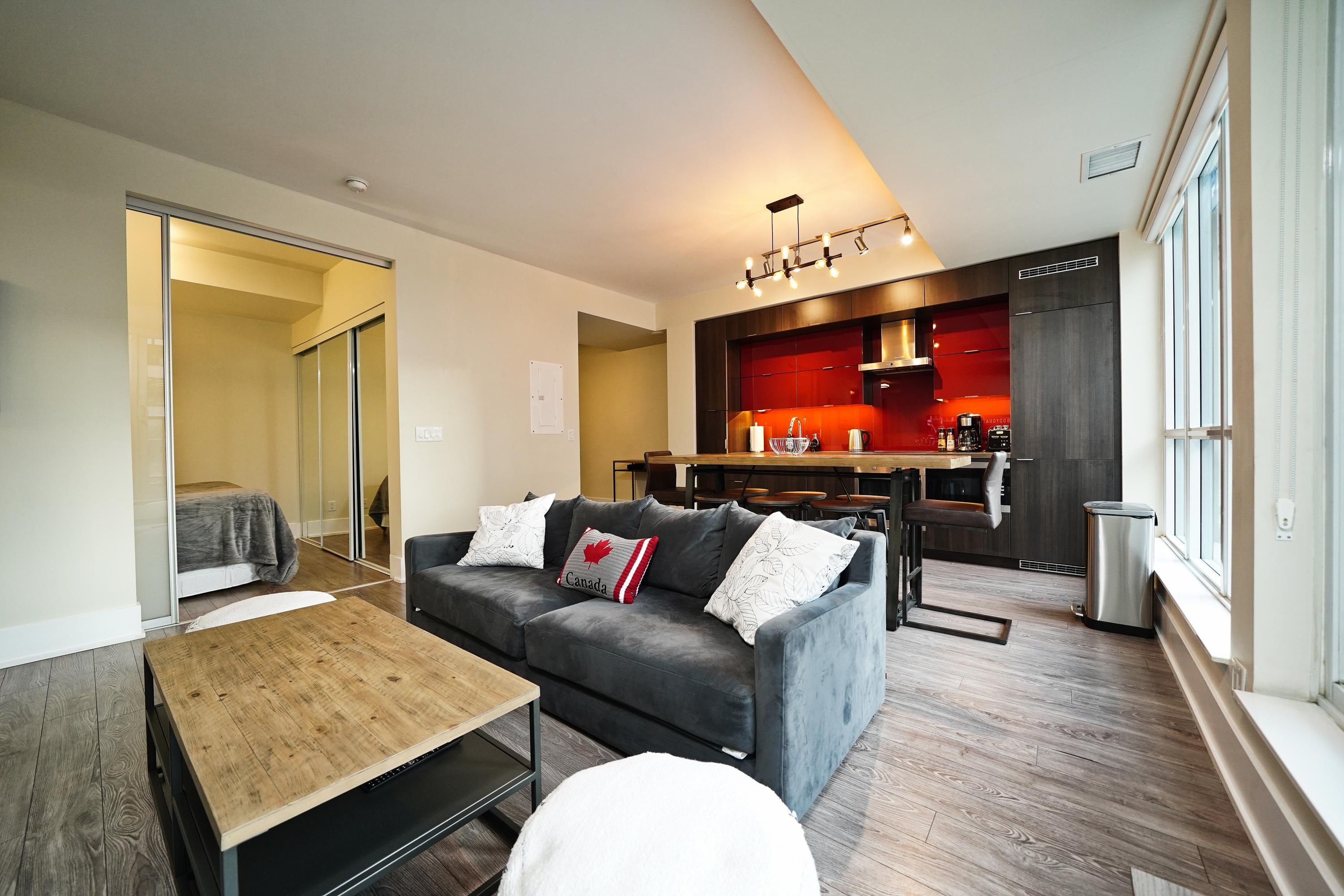 Una sala moderna con un sofá, una mesa de centro y una kitchenette al fondo.