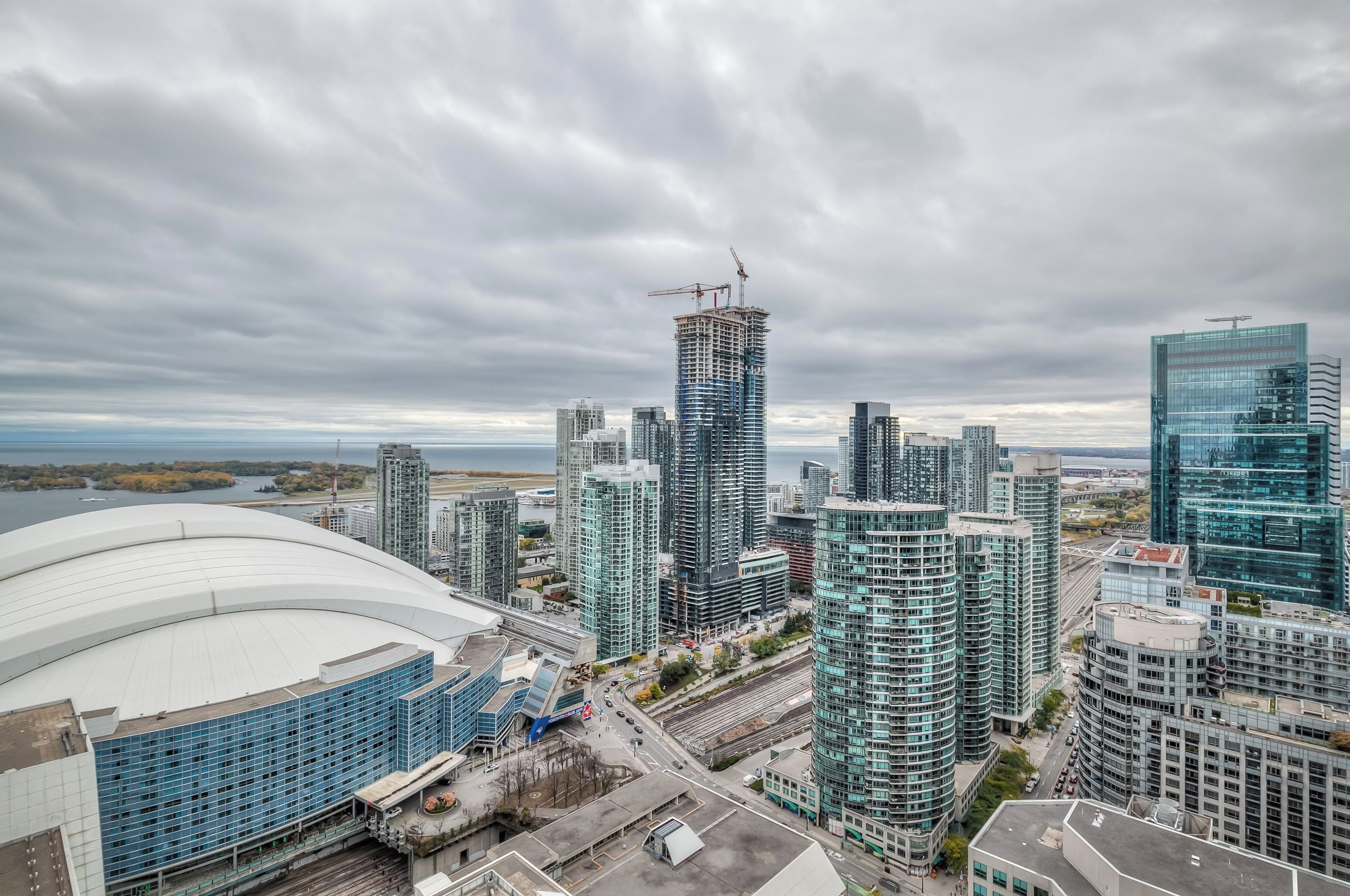 A cityscape with modern high-rise buildings, a large stadium, and a construction crane.