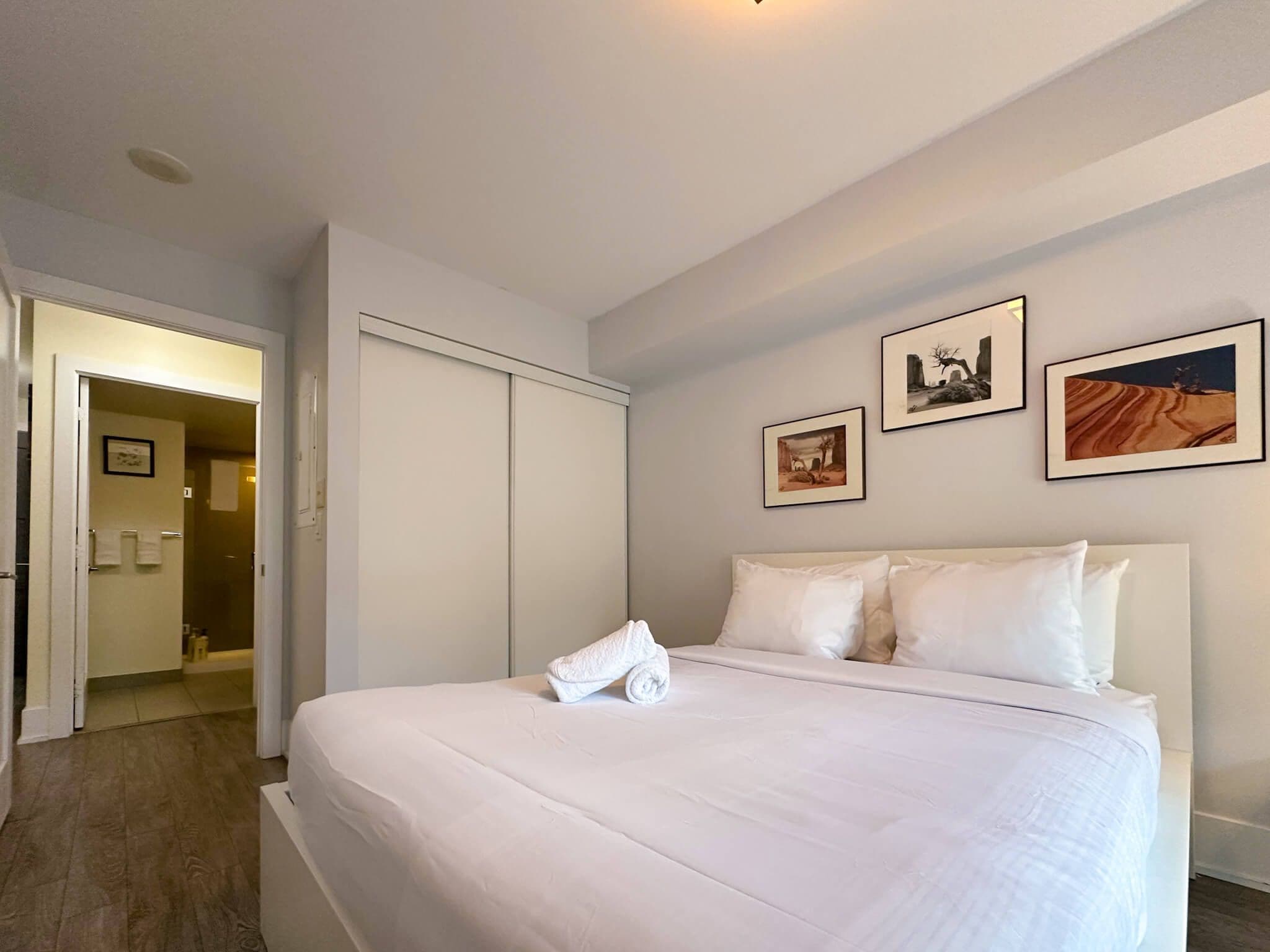 Quarto de hotel com uma cama grande, um guarda-roupa e um banheiro visível através de uma porta aberta.