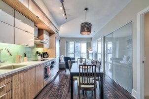 A modern kitchen with wooden cabinets, a dining area with a table and chairs, and a large window providing natural light.