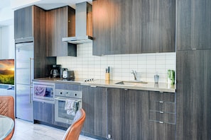 Una cocina moderna con armarios de madera oscura, electrodomésticos de acero inoxidable y salpicadero de azulejos.