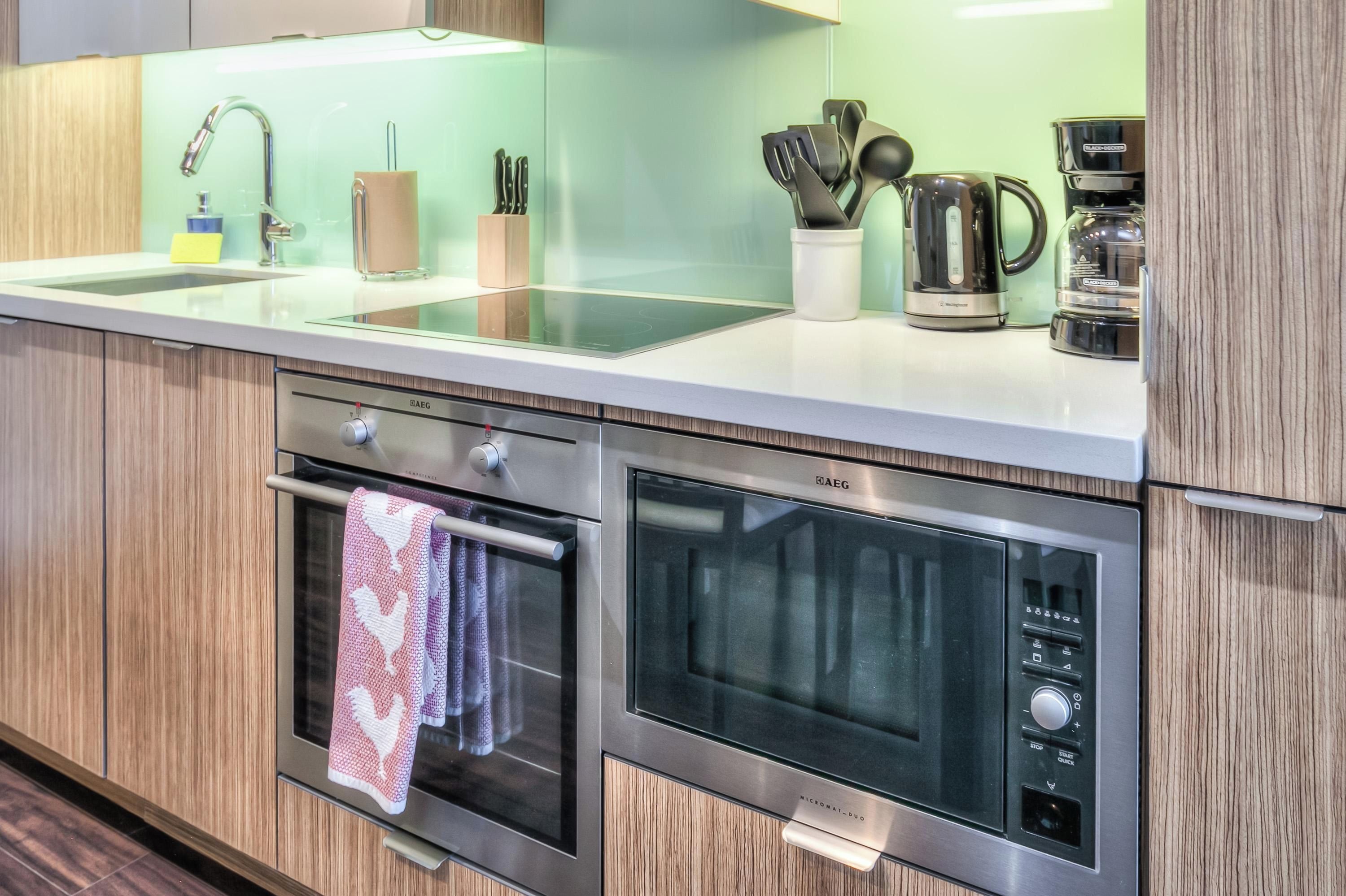 A modern kitchen with a stainless steel range, oven, and microwave. There are knives, a kettle, and a coffee maker on the countertop.