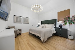 Una camera da letto moderna con un letto, comodini, una sedia, una lampada a sospensione e una pianta in vaso.