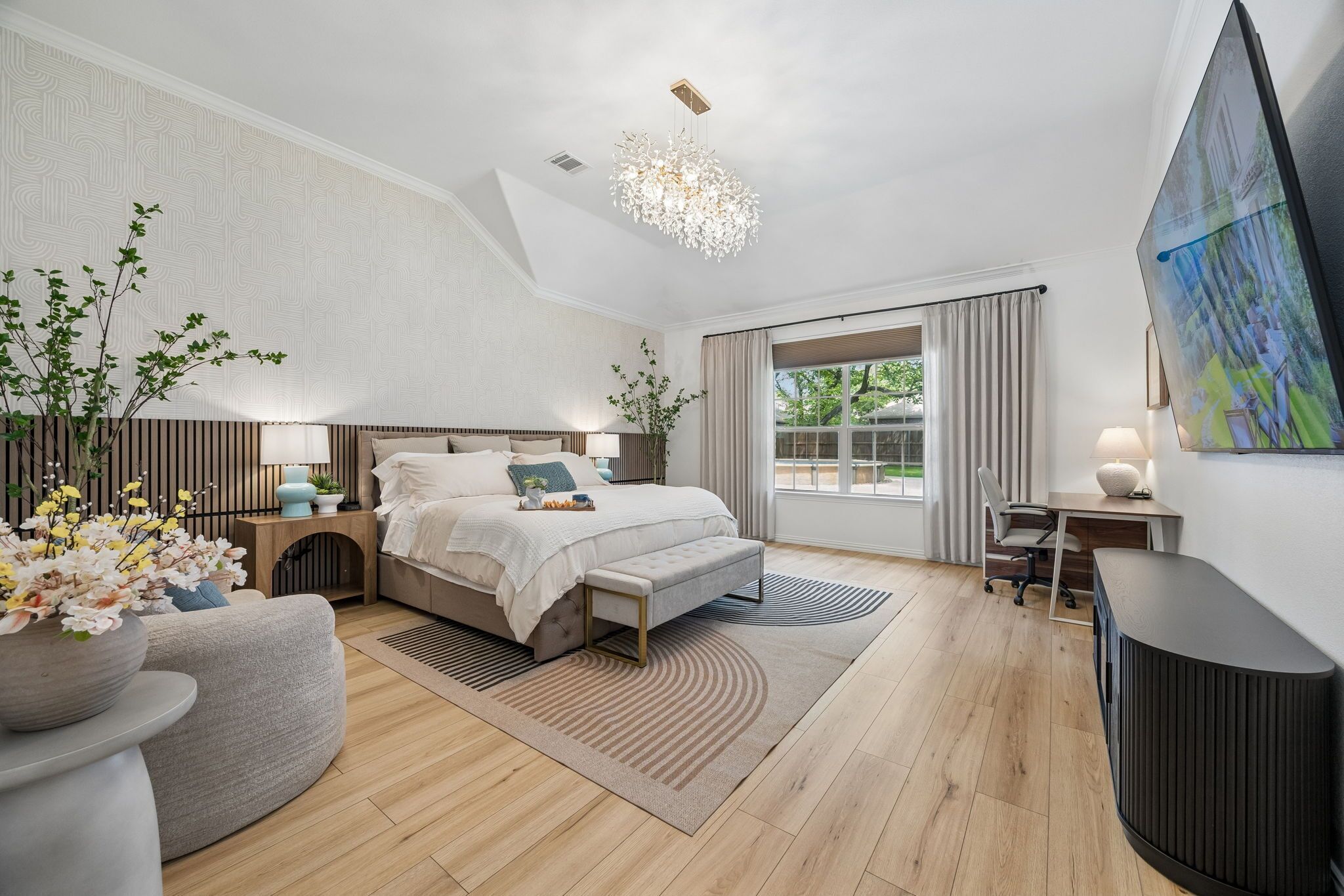 Een moderne slaapkamer met een bed, nachtkastjes, een bureau, een stoel, een groot raam en een plafondlamp.